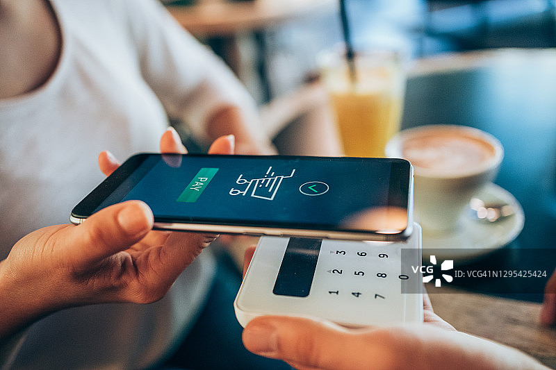 女人在咖啡馆用智能手机进行非接触式支付图片素材