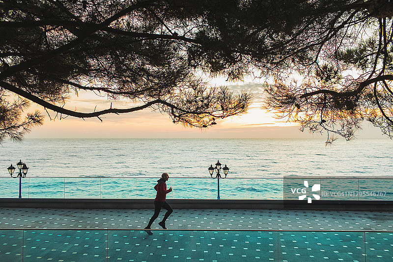 男人在日出时空无一人的海滨长廊上跑步图片素材