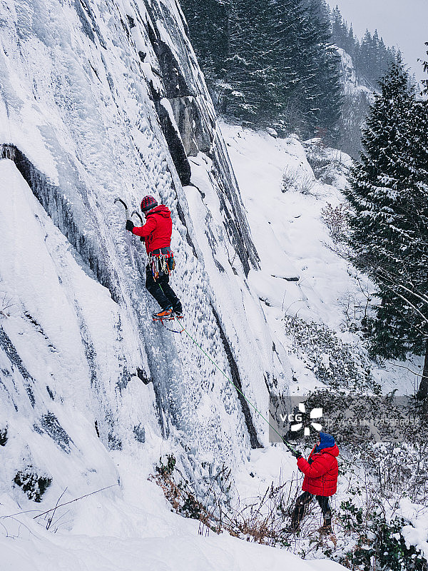 攀冰者及其保护者在加拿大斯阔米什攀登冰冻瀑布图片素材