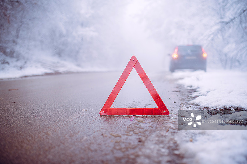 暴风雪中损坏的汽车与警示三角标志图片素材