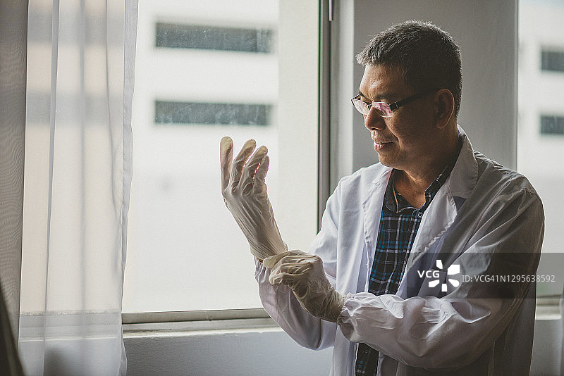 亚洲医生戴着乳胶手套，穿着实验服图片素材