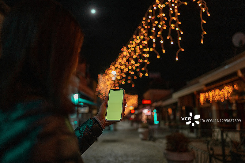 夜晚街头使用带色度键屏幕手机的女人图片素材