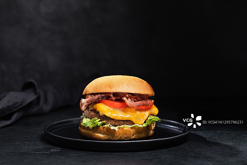 黑色背景上的培根芝士汉堡图片素材