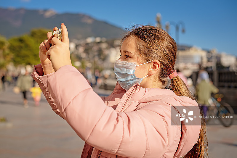 戴口罩用手机拍照的女孩图片素材
