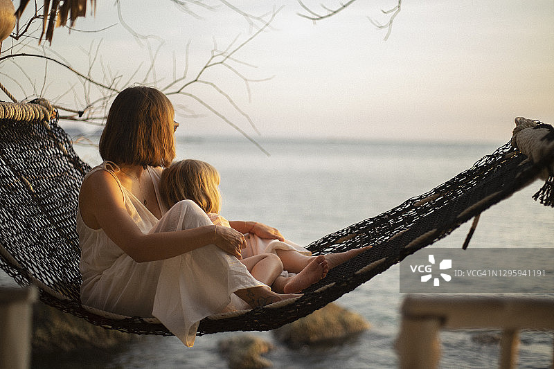 宁静的母女在吊床上享受海洋日落图片素材