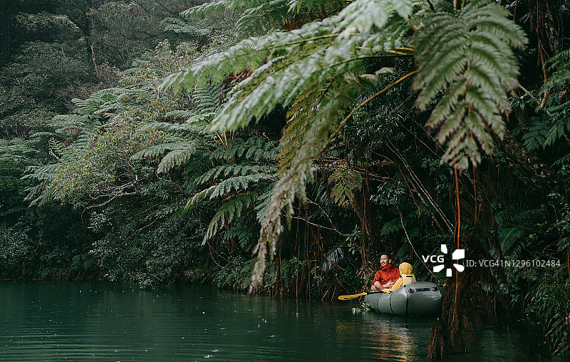 父亲和孩子在冲绳的丛林河流中划着充气筏，日本图片素材