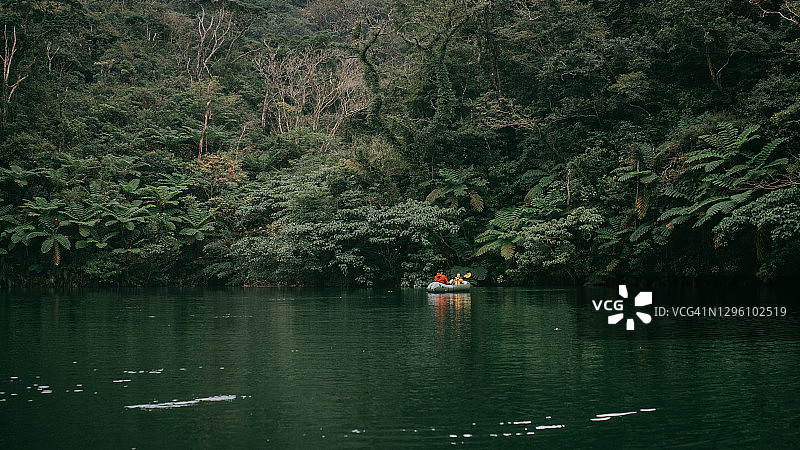 父亲和孩子在冲绳日本的丛林河流上划皮划艇图片素材
