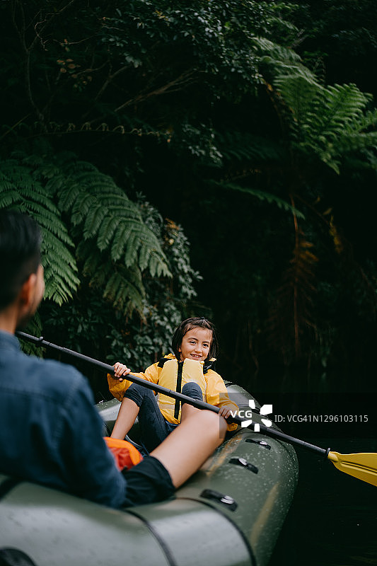 小女孩和父亲在日本的丛林河流中划着充气艇图片素材