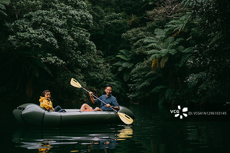父亲与孩子在日本冲绳的丛林河流上享受皮划艇乐趣图片素材