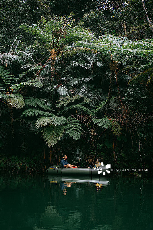 父亲和孩子在冲绳日本的丛林河流上划皮划艇图片素材