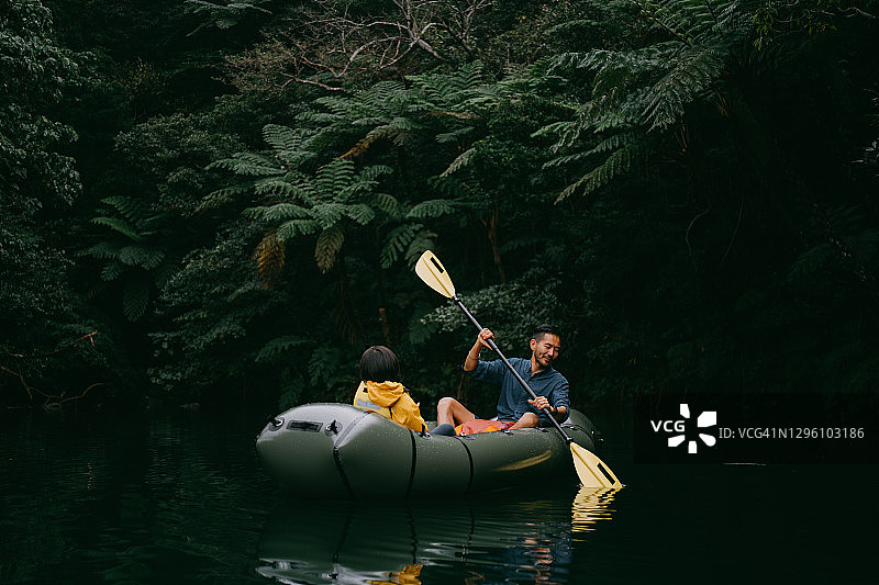 快乐的男人与孩子在冲绳丛林河流上划皮划艇，日本图片素材
