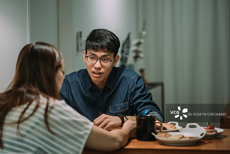 亚洲华人青年和他的妹妹在家中用餐区交谈图片素材