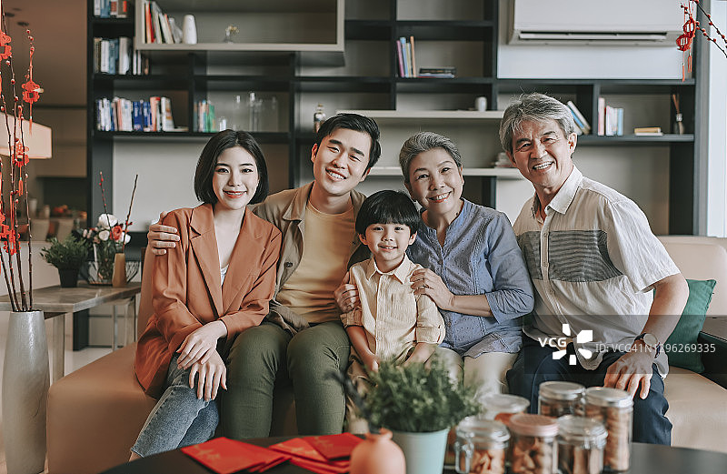 中国新年：客厅里 multigenerational 家庭坐在沙发上，看着相机，笑容满面图片素材