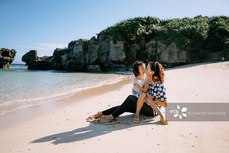 母亲在海滩上拥抱年幼的女儿图片素材