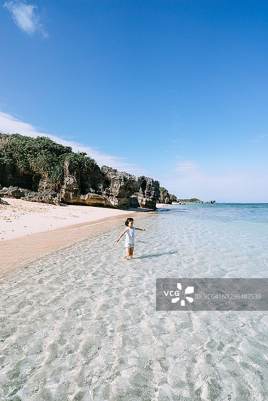 年轻女孩在日本冲绳热带海滩的清水中玩耍图片素材