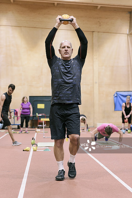 年长的男人举着壶铃图片素材