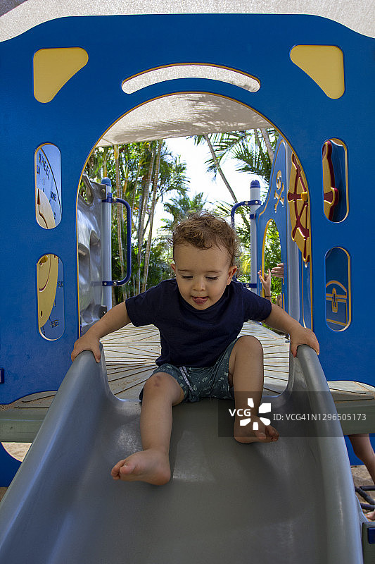 在操场滑梯上玩耍的幼儿男孩画像图片素材