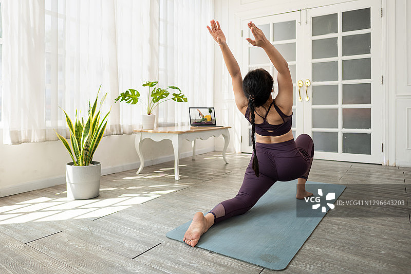 教练视角的互动在线健身。使用笔记本电脑在客厅会议室进行的瑜伽在线课程。在线教学或电子学习的新常态。图片素材