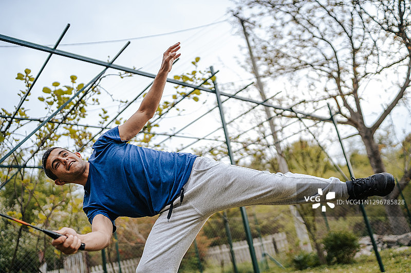 在后院打羽毛球的年轻男人图片素材