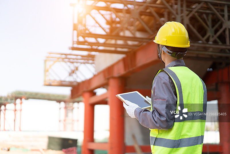 亚洲工人在建筑工地使用平板电脑图片素材
