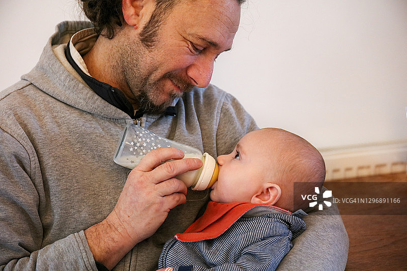 父亲给新生儿子喂奶粉图片素材