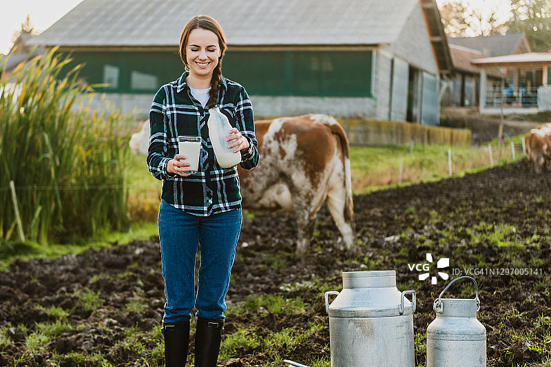 年轻女人在奶牛场拿着装有牛奶的玻璃瓶图片素材