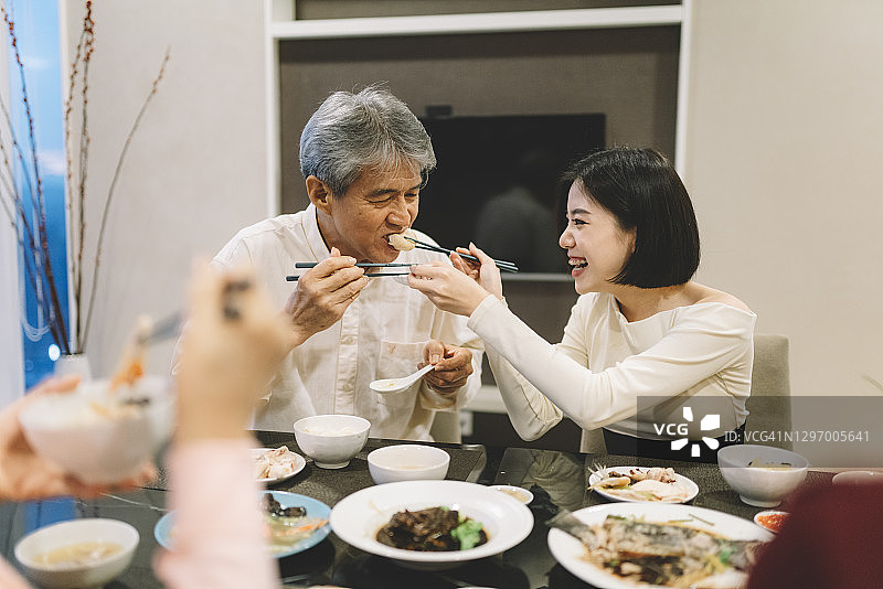 中国农历新年团圆饭上女儿喂父亲吃饭图片素材
