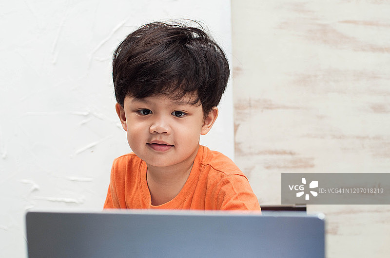 一名东南亚幼儿在家中使用笔记本电脑参加在线课程图片素材