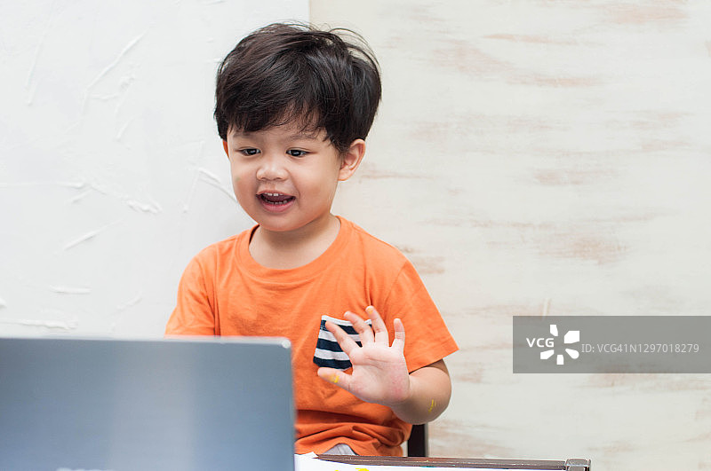 一名东南亚幼儿在家中使用笔记本电脑参加在线课程图片素材