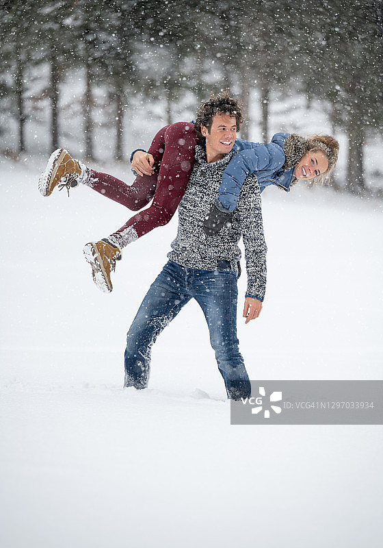 在雪地里玩耍的情侣，快乐的表情，大雪纷飞图片素材