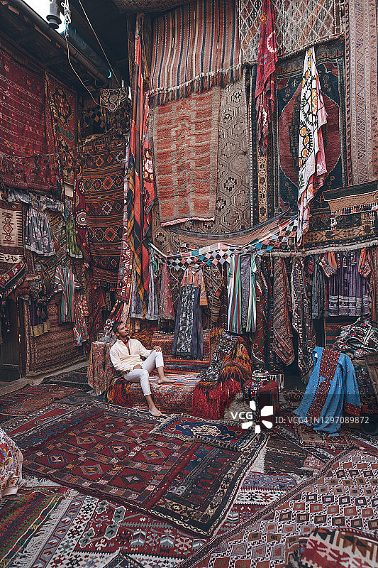 在土耳其卡帕多奇亚传统地毯店享受假期的年轻男游客图片素材