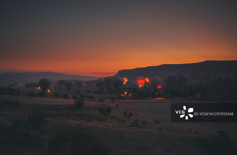 土耳其卡帕多奇亚格莱梅，日出时分飞越岩层的热气球图片素材