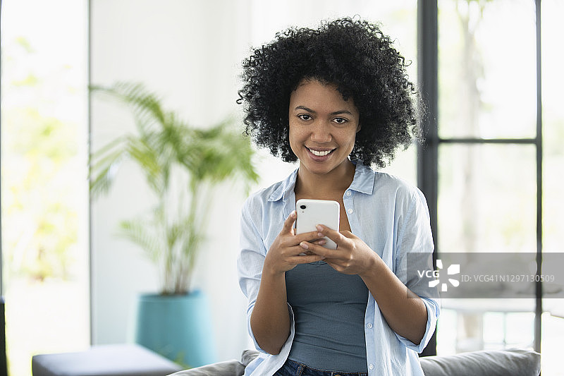 微笑的年轻女子在智能手机上发短信图片素材