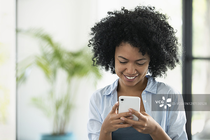 使用智能手机的微笑年轻女人图片素材