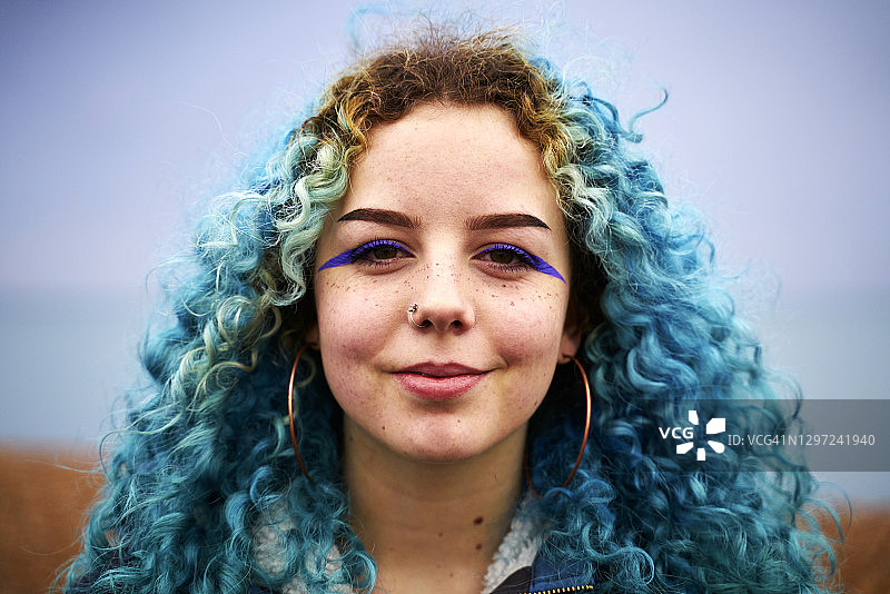 对着镜头微笑的蓝色卷发少女图片素材