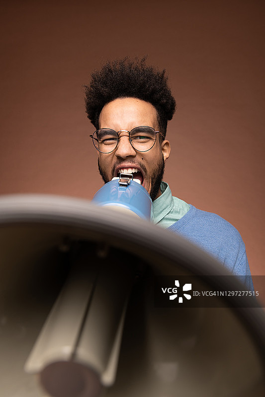 戴眼镜的年轻混血商人用扩音器喊话图片素材