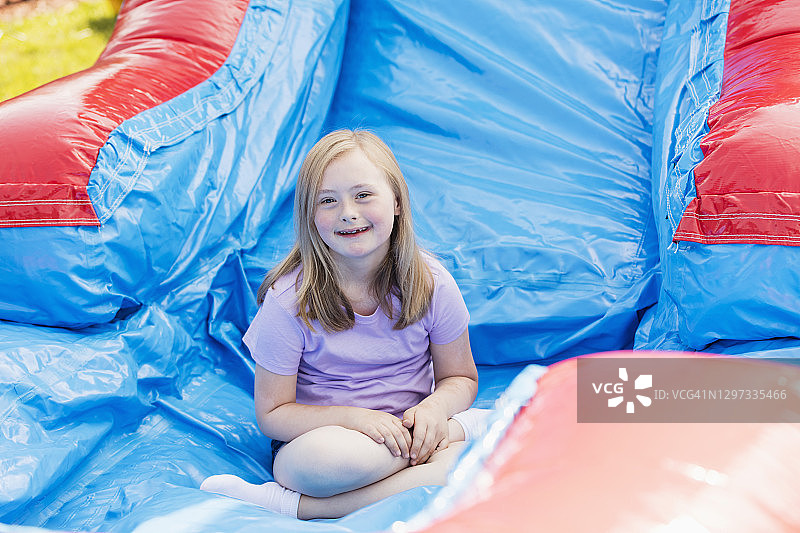 唐氏综合征女孩玩巨型充气滑梯图片素材