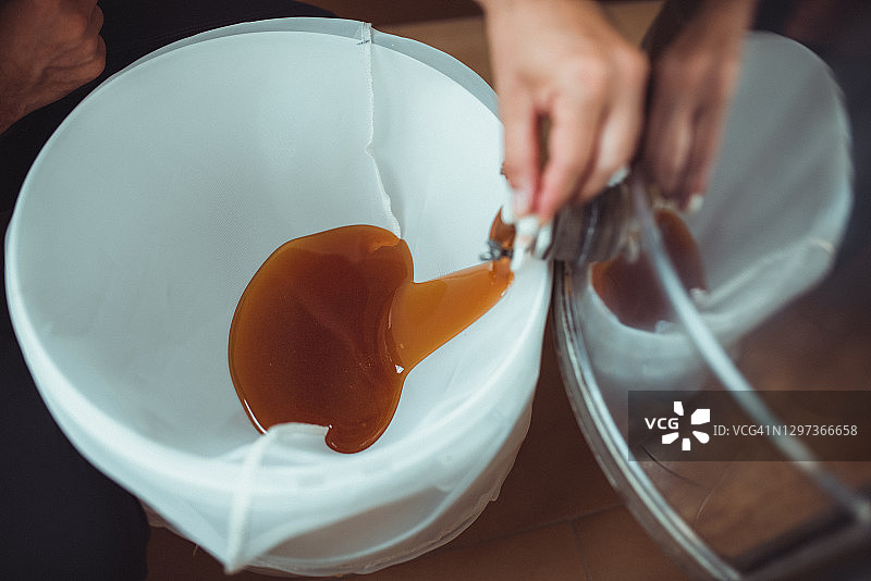 蜂蜜提取：养蜂人打开蜂蜜提取器的水龙头，蜂蜜流出图片素材