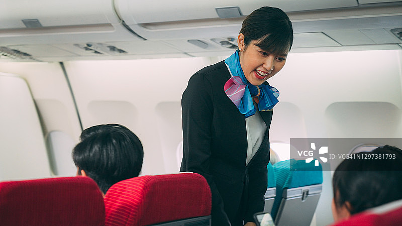 美丽的空姐正在关闭飞机上的头顶行李舱图片素材