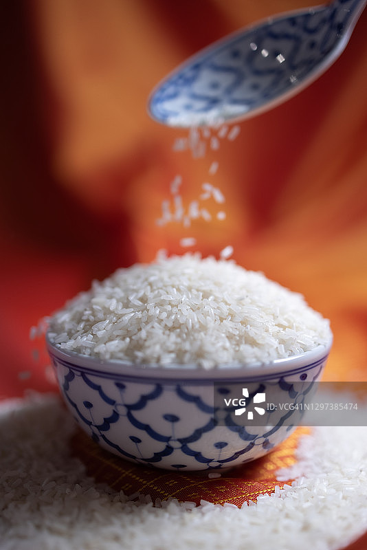 勺子将米粒滴入传统陶瓷碗中图片素材