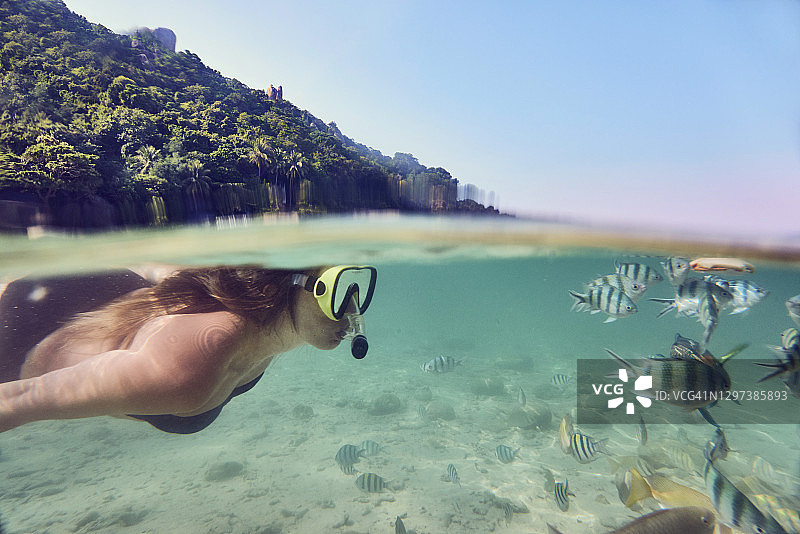 美丽的女人在温暖的海洋中与热带鱼一起浮潜图片素材
