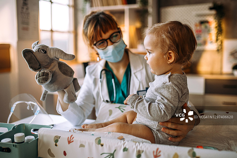 医生在诊所里和男婴患者玩耍图片素材