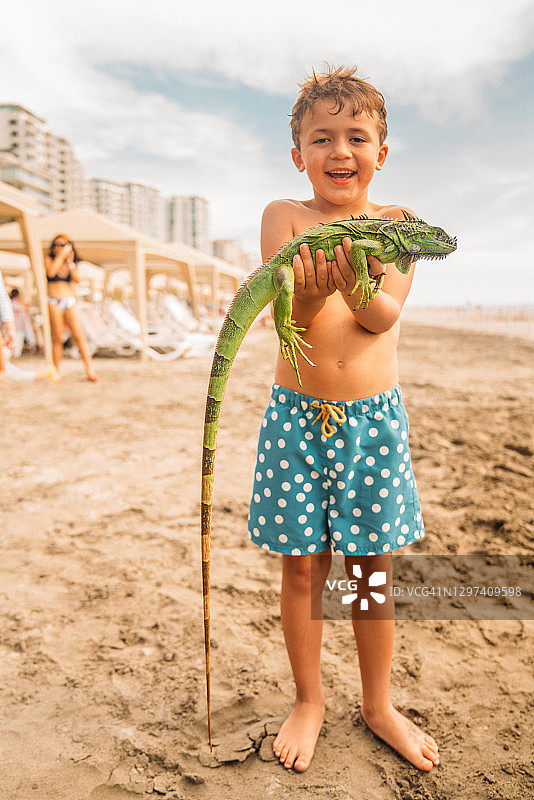 男孩在海滩拿着鬣蜥图片素材
