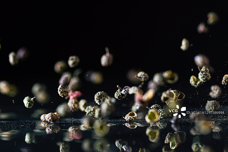 黑色背景中飞舞的绿色花椒图片素材