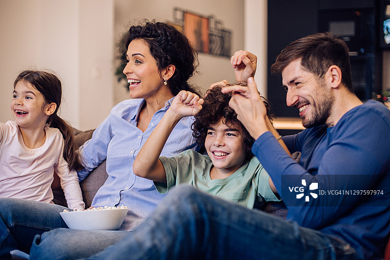 观看电影并欢呼雀跃的兴奋家庭肖像图片素材