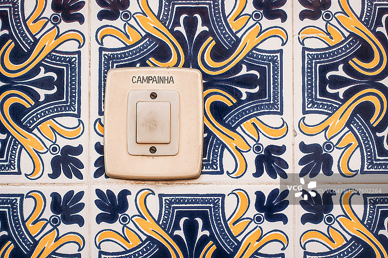 葡萄牙外墙上的老门铃按钮，带有蓝色、黄色和白色图案瓷砖图片素材