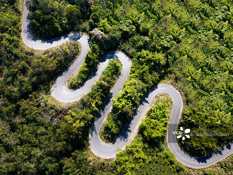 泰国清莱府高地山区绿色森林中的弯曲道路航拍图片素材