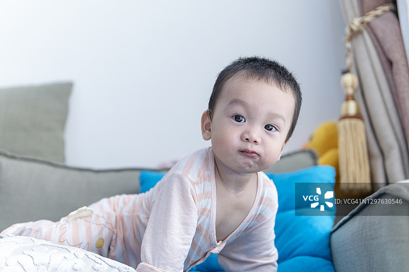 可爱的亚洲宝宝在客厅沙发上吃面包玩耍图片素材