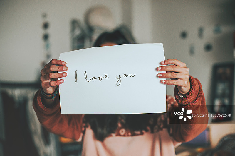 女人拿着一张写着“我爱你”的纸图片素材
