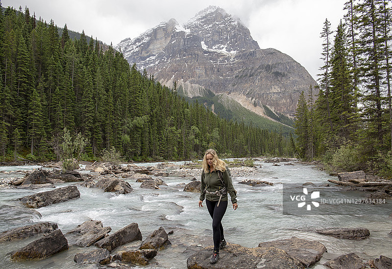 徒步女性在冰川河流的岩石间跳跃图片素材